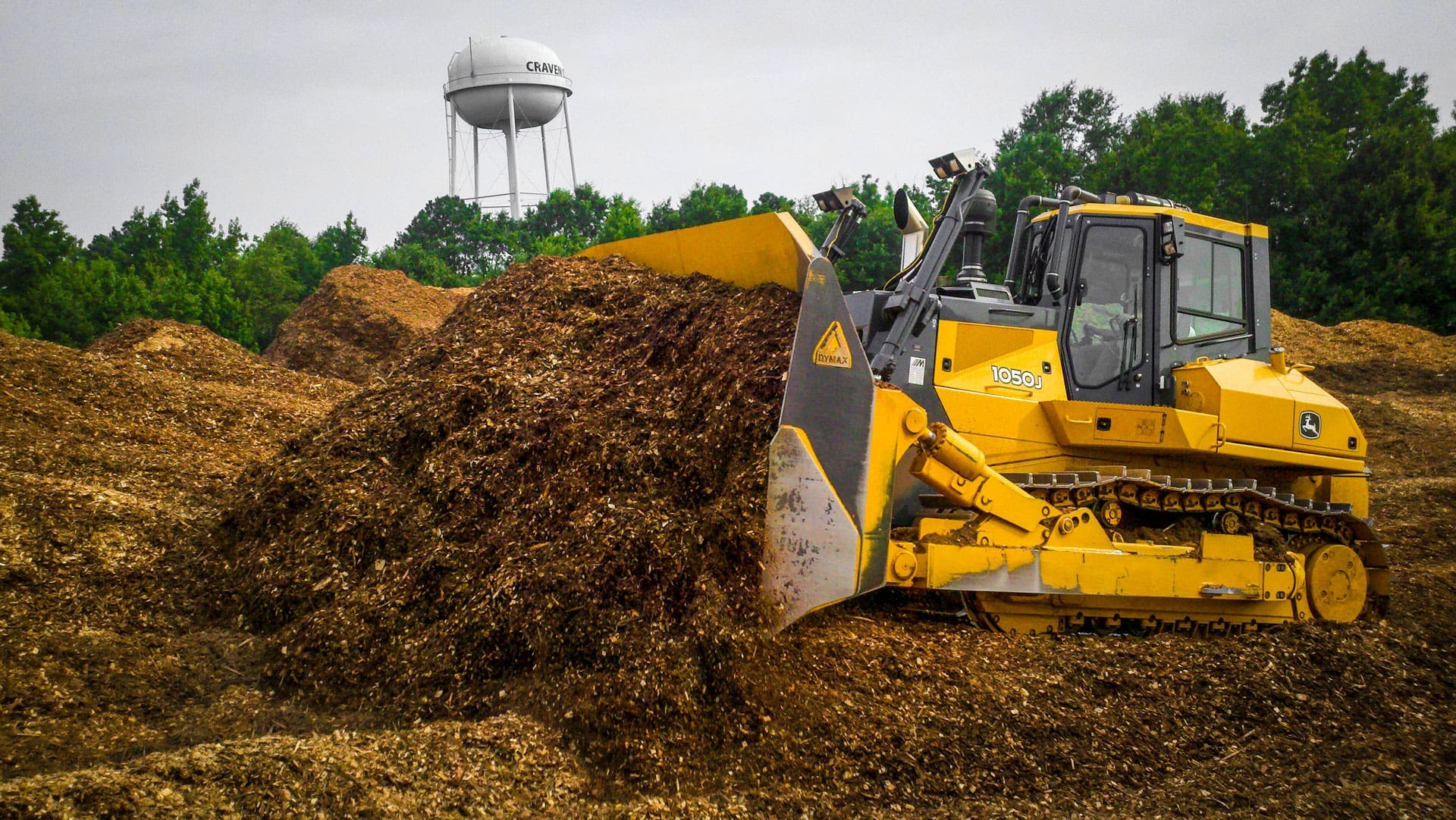 Dymax Woodchip Dozer Blade on a John Deere 1050J pushing a full pile of wood chips