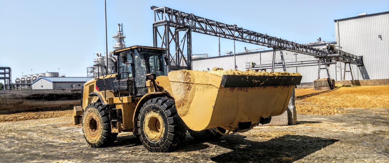 Caterpillar wheel loader with a Dymax Bonus Bucket loading wet distillers grain at an ethanol processing plant in Nebraska.