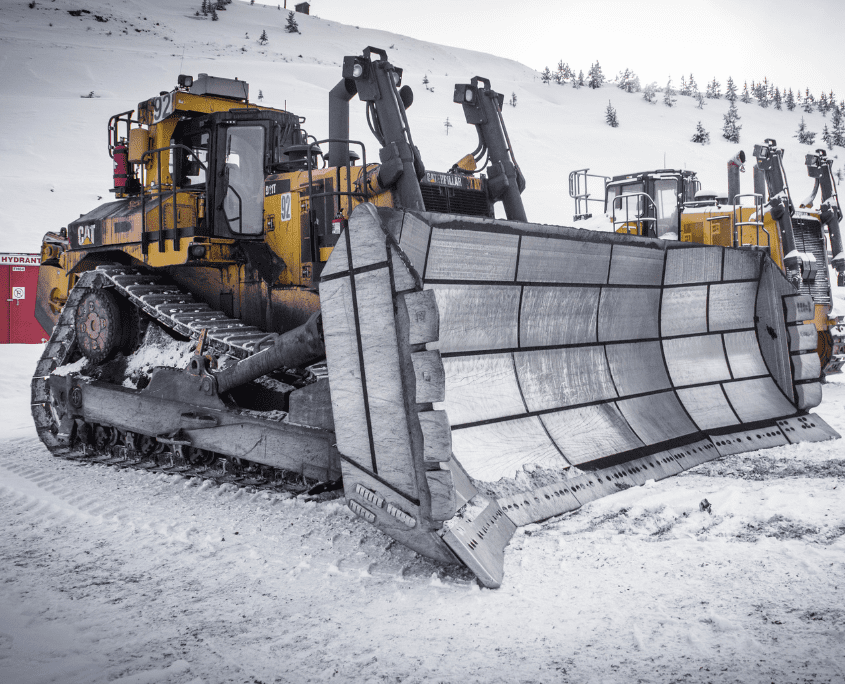 Reclamation mining dozer blade attachment on a dozer with a snowy backdrop