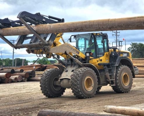 heel loader handling utility poles with a Dymax pole handling fork attachment