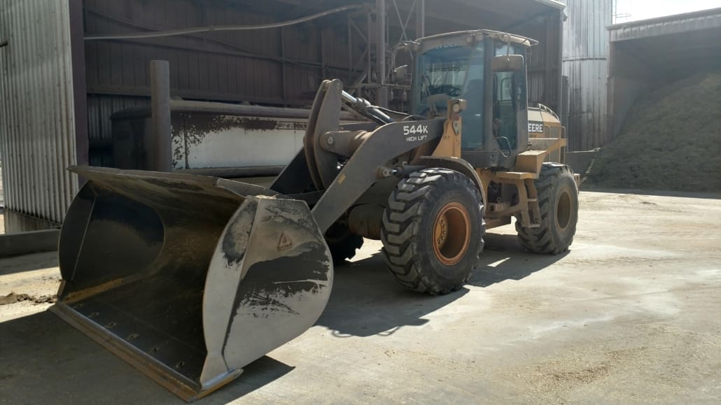 Feedyard Light Material Bucket on Wheel Loader Close view of a Dymax feedyard light material bucket mounted on a wheel loader in a feedyard setting